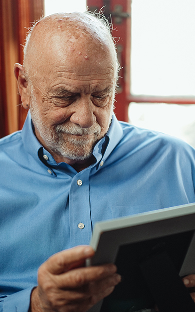 portrait version of a man holding a framed photo of his loved one