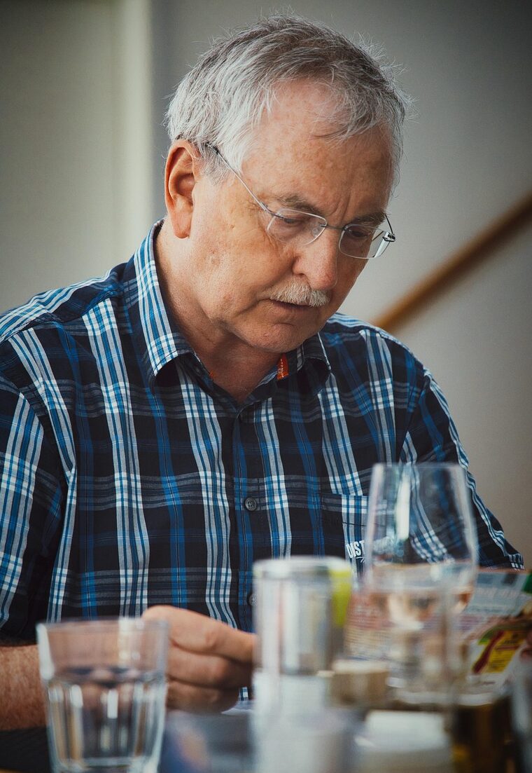 Man in blue shirt reading magazine at breakfast table
